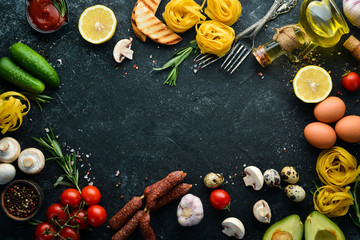 Dry pasta and ingredients for cooking. Black food background. Free space for your text.