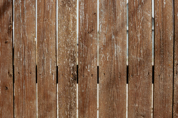 Old rustic brown street fence under the shining sun. The texture of natural wood. Template for design.