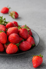 Fresh strawberries in a bowl on a gray table. Strawberry close-up, selective focus.