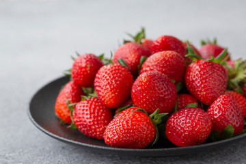 Fresh strawberries in a bowl on a gray table. Strawberry close-up, selective focus.
