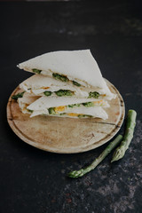Tasty appetizing toasts with asparagus, eggs, cheese. Soft-boiled egg asparagus sandwich. Tramezzino con uovo e asparagi 