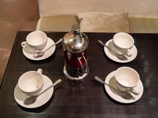 four empty tea cups and a French press are on a wooden table in the cafe. top view