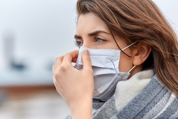 health, safety and pandemic concept - young woman wearing protective medical mask outdoors