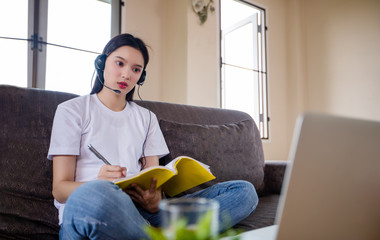 Asian happy woman student wear headphones study online watching webinar podcast on laptop listening...