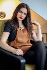 Fototapeta premium Jeune femme assise dans un fauteuil en salopette marron