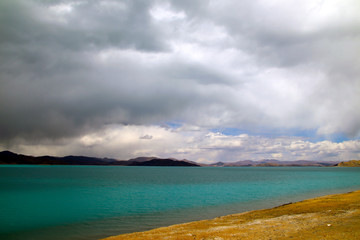 Plateau holy lake, blue-green lake water, coffee-colored distant mountains, rising water vapor and clouds