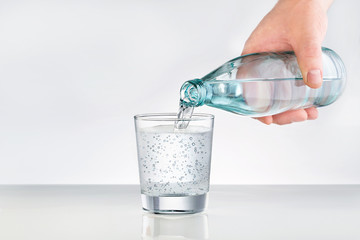Male hands pouring bottled water into glass. Water glass with copy space. Mineral water for healthy lifestyle.