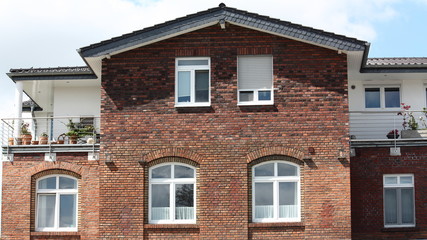 Backsteinfassade mit Fenstern und Dachterrasse