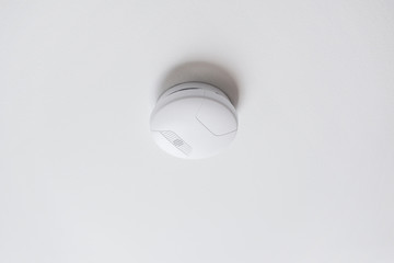fire alarm system, safety and security concept - domestic smoke detector or sensor on white ceiling