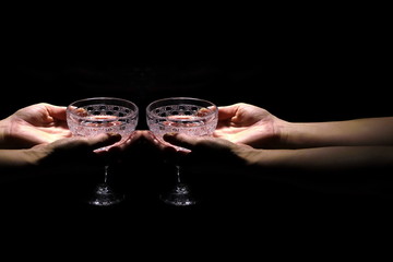 two hands are holding empty wine glasses on a dark background 1