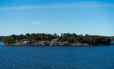 Fototapeta na wymiar Picturesque summer houses painted in traditional falun red on dwellings island of the Stockholm archipelago in the Baltic Sea in the early morning.