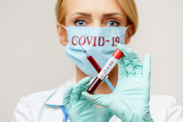 medical doctor nurse woman wearing protective mask and gloves - holding virus blood test tube and syringe