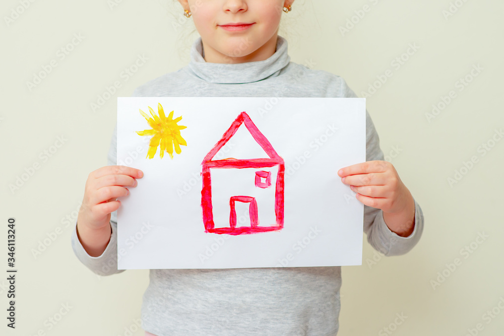 Wall mural Child is holding picture of red house with sun on yellow background. Elementary school of drawing.