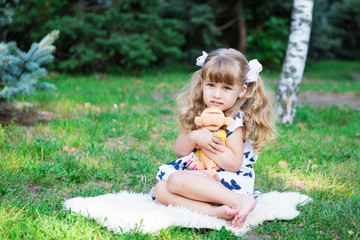 girl sitting on grass hugs a toy
