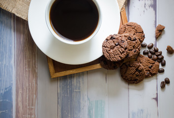 Top view coffee cups and chocolate chip baked cookies .on a wooden table with a space to put text