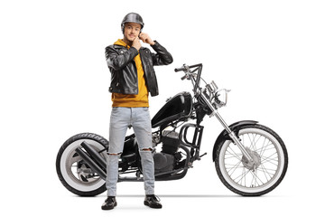 Fototapeta na wymiar Young biker taking off helmet and standing next to chopper motorbike