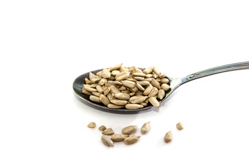 peeled sunflower seeds in a spoon isolated on white background.
