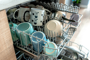 Bright colorful dishes. Open dishwasher. Washing dirty dishes tableware on the tray in dishwasher machine in the kithcen, selective focus. Space for text.