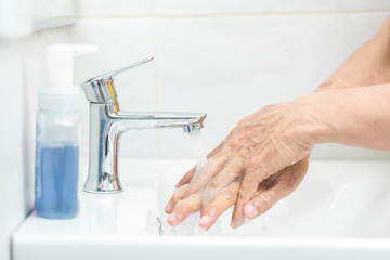 Man hands use soap and washing her hands under the faucet. Hygiene concept