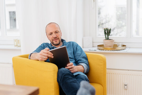 Middle-aged man relaxing reading on a tablet