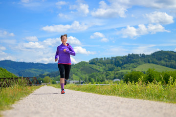 Woman jogging along a country road in spring