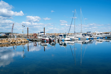 Fototapeta na wymiar Simrishamn, Sweden - May 13, 2019: Boats at the marina on sunny day with reflectiom on water
