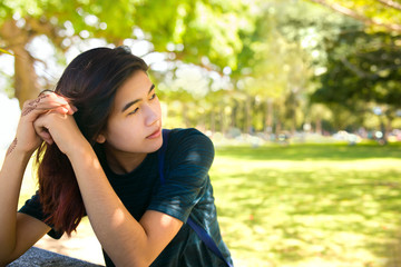 Teen girl sitting at picnic table outdoors thinking, sunny day