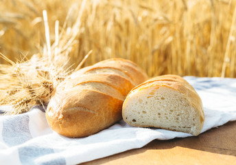 Bread on the table and wheat in the field of wheat and sunny day