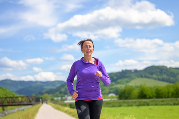 Fit active woman jogging in a spring landscape