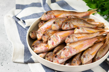 Black sea barabulka fish in a white ceramic bowl on a light gray kitchen table. A lot of fish red mullet. Black sea barabulka