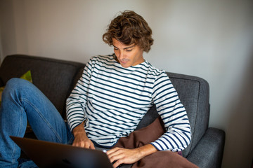 young man relaxing at home looking at laptop computer