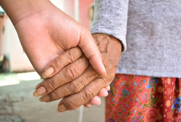 Hands of two people represent family warmth and care for the elderly.