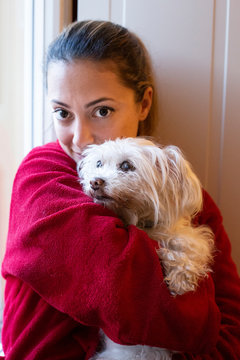 ritratto di una ragazza chiara con gli occhi grandi e scuri vestita di rosso vicina al suo cane di razza maltese
