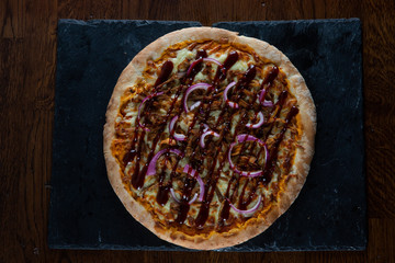 Mixed herb, onion and balsamic glaze pizza on slate with dark oak background