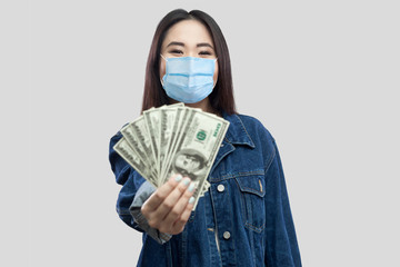 Portrait of successful attractive young asian woman with medical mask standing, holding dollars,...
