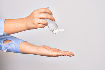 Young caucasian woman pouring alcohol liquid from a bottle to clean hands