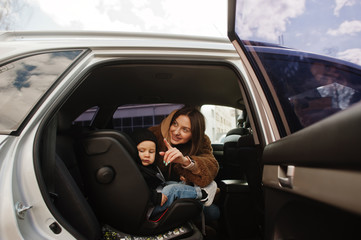 Young mother and child in car. Baby seat on chair. Safety driving concept.