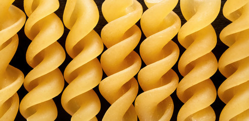 Uncooked rotini or fusilli pasta in a row