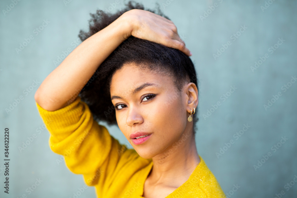 Wall mural beautiful young african american woman with hand in hair by green background