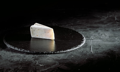 Delicious cheese on dark background. Copy space