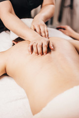 Hands of a masseuse on a female back during work - massage salon - spa treatments for female beauty and health