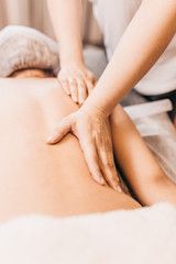 Fototapeta na wymiar Hands of a masseuse on a female back during work - massage salon - spa treatments for female beauty and health