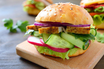 Homemade bun with turkey breast, vegetables, herbs on a wooden board.  Sandwich for lunch. Close up