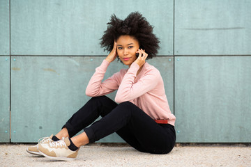 beautiful african american woman sitting on floor outside talking with cellphone