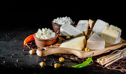 Different sorts of cheese. Сheese delicatessen on a black concrete background