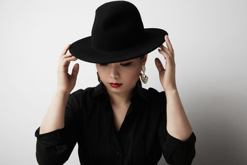 Beauty portrait of sensual asian young woman wearing black hat posing on white background. White background.