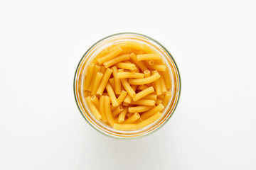 Ziti rigati or tubini pasta in a jar on white background