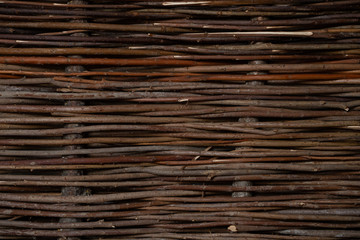 Wicker fence made of flexible wood (willow or hazel). The texture of the trunk of a natural tree. Garden decor or interior decor for the background.