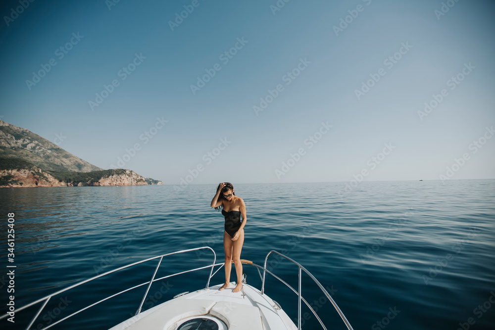 Wall mural young woman in swimwear standing on yacht front