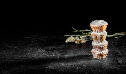 Fototapeta na wymiar Delicious muffins powdered with icing sugar on dark background